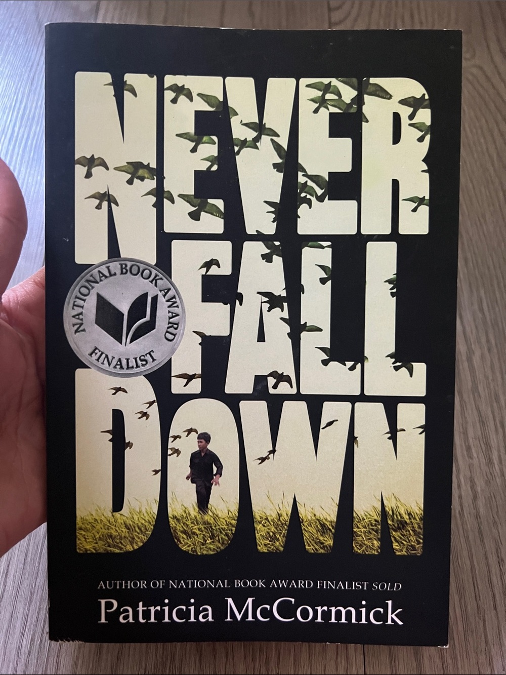 Never Fall Down by Patricia McCormick - Yellow & Black Paperback